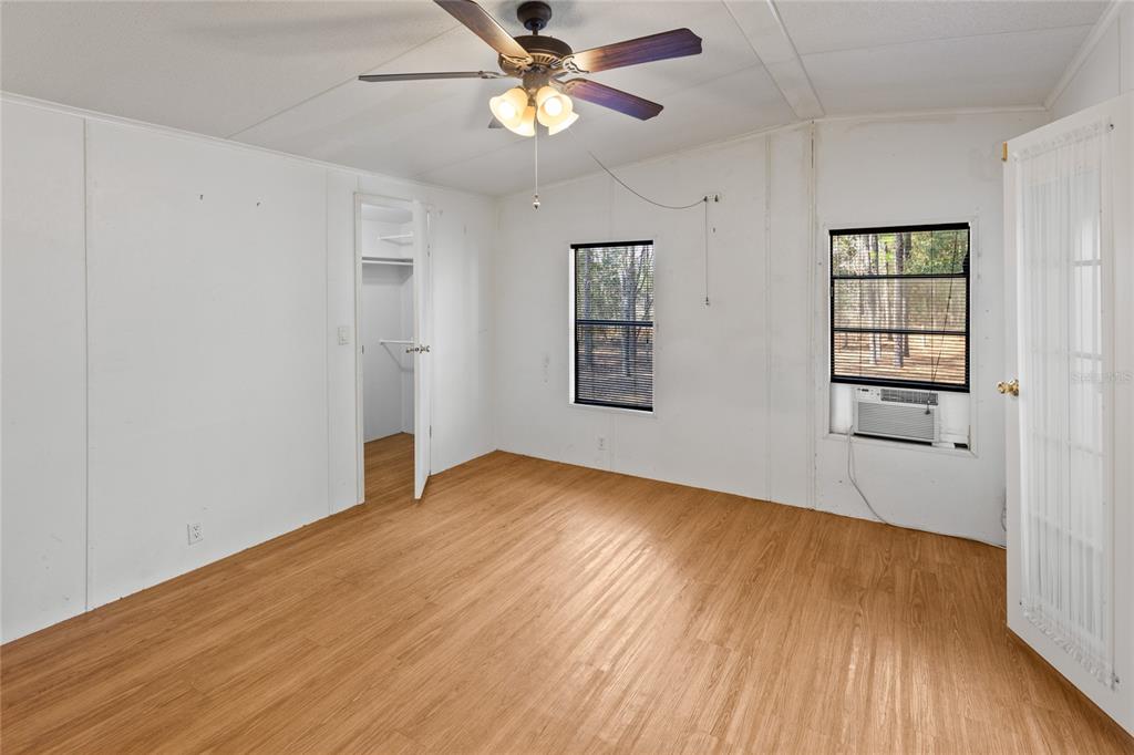 110 Hill Top Loop Hawthorne, FL 32640 - Photo 28 of 52 an empty room with wooden floor chandelier fan and windows