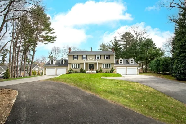 a front view of a house with a yard and trees