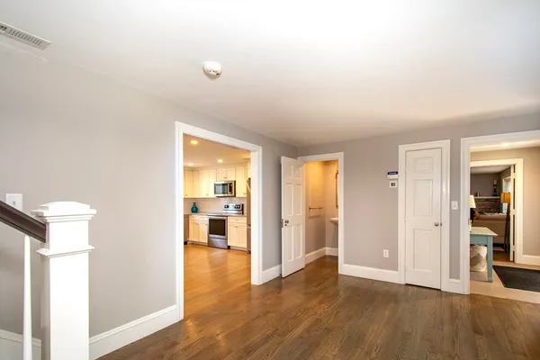 a view of a hallway with wooden floor and a bathroom