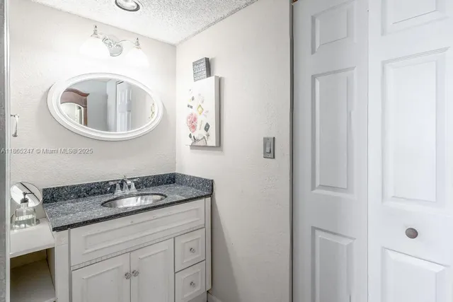 a bathroom with a granite countertop sink and a mirror