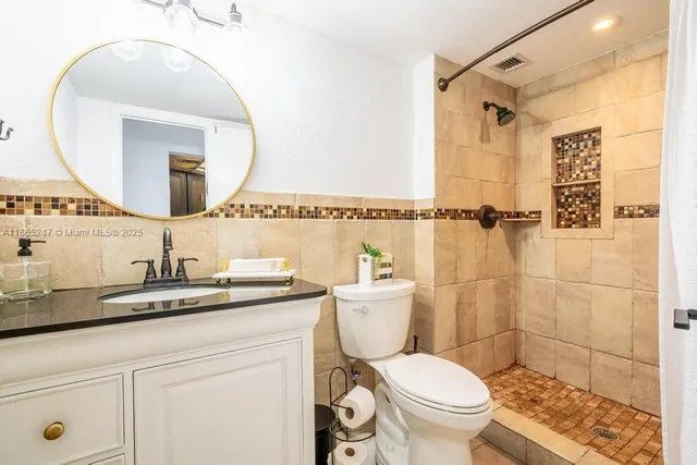 a bathroom with a granite countertop sink mirror vanity and toilet