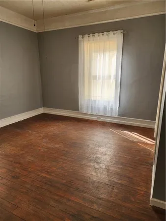 an empty room with wooden floor and chandelier fan