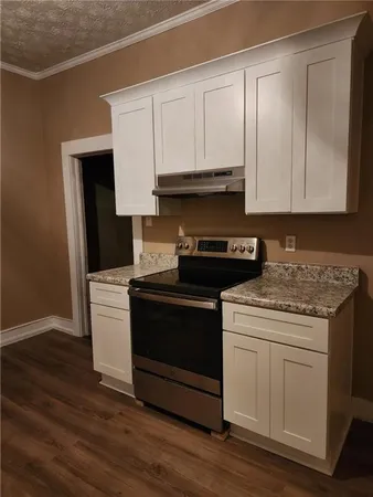 a kitchen with granite countertop a stove and a white cabinets