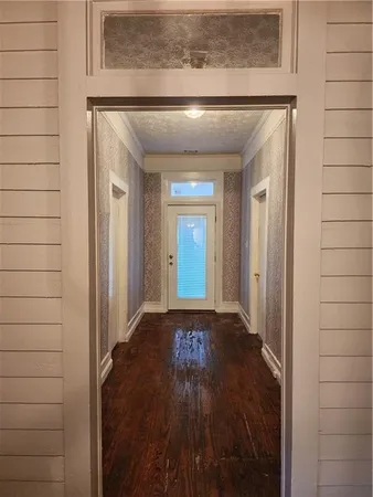 a view of a hallway with wooden floor and a bathroom