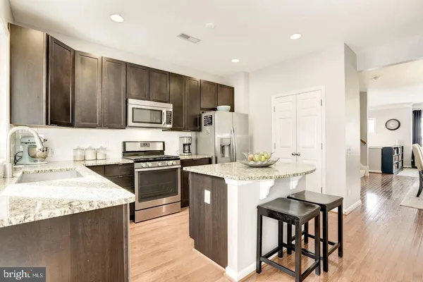 a kitchen with stainless steel appliances kitchen island granite countertop a stove a sink a microwave and a refrigerator