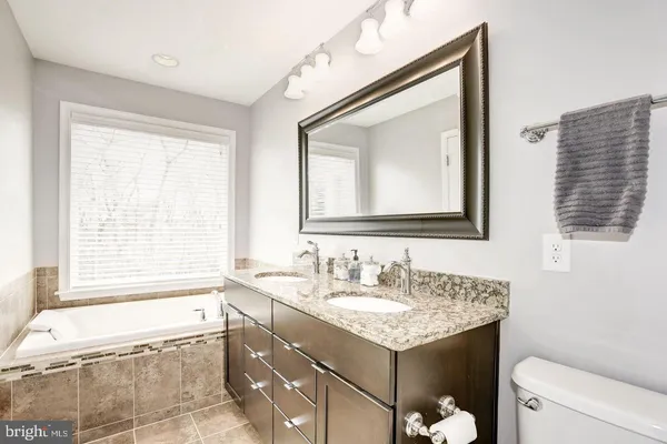 a bathroom with a granite countertop sink mirror and a bathtub