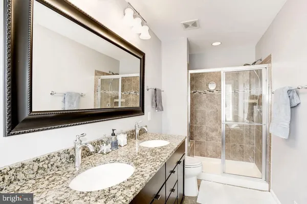 a bathroom with a granite countertop sink mirror and a shower