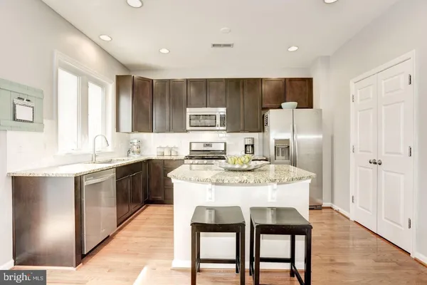 a kitchen with stainless steel appliances granite countertop a dining table chairs refrigerator and cabinets
