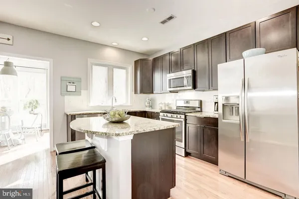 a kitchen with kitchen island granite countertop a sink stove and refrigerator