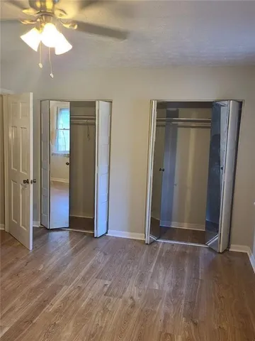 an empty room with wooden floor a chandelier fan and closet area