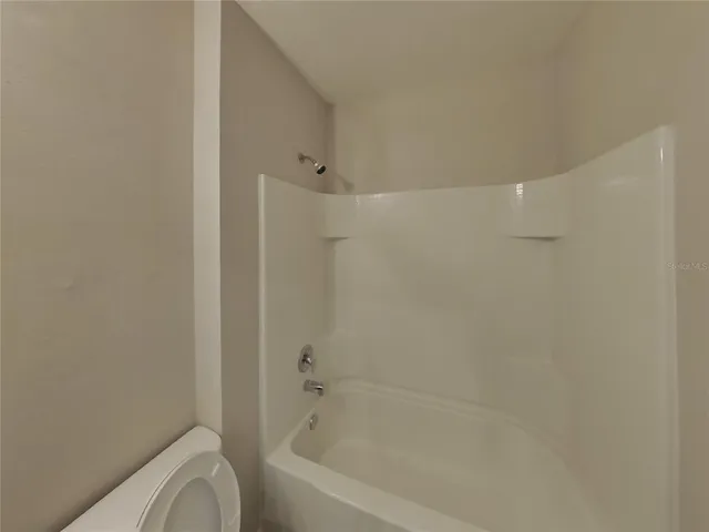a bathroom with a granite countertop bathtub shower and toilet