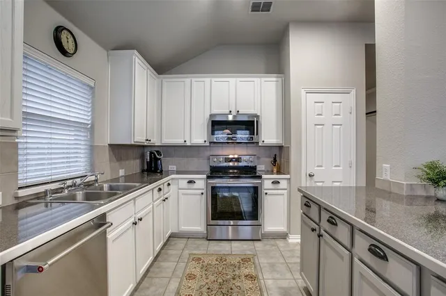 a kitchen with stainless steel appliances kitchen island granite countertop a refrigerator a table and chairs in it