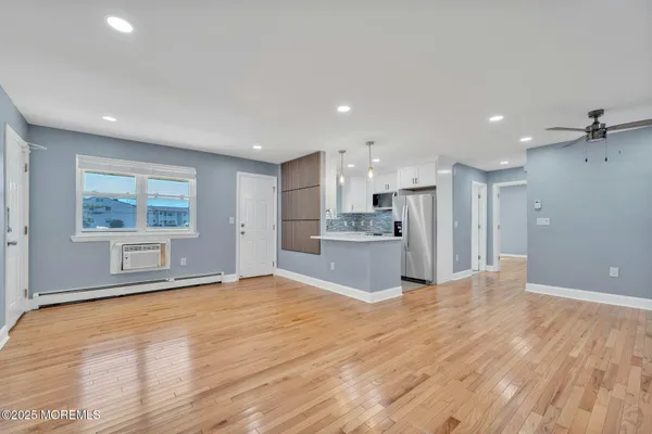 a view of a kitchen with kitchen island wooden floor appliances and cabinets