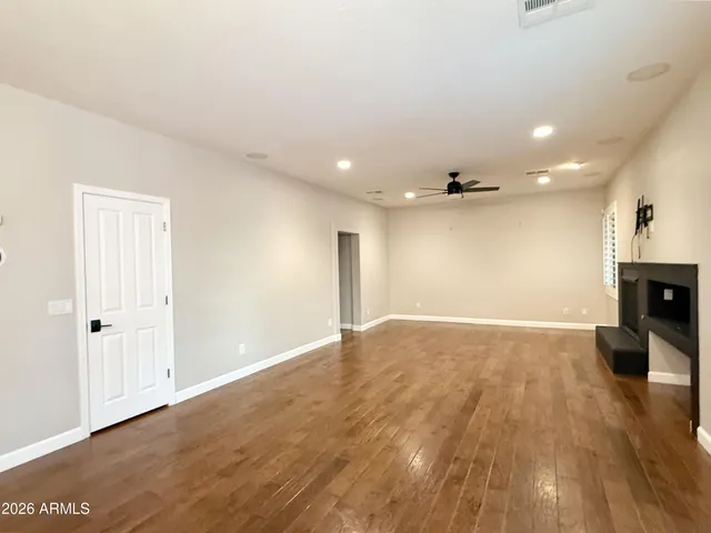an empty room with a chandelier fan and windows