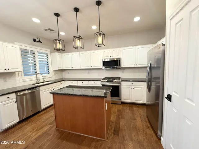 an empty room with wooden floor fireplace and windows