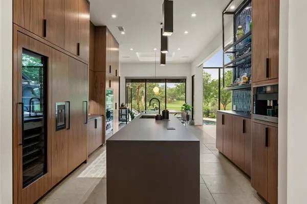 a kitchen with stainless steel appliances granite countertop a refrigerator a oven a sink and a large window