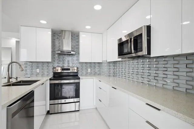 a kitchen with stainless steel appliances granite countertop white cabinets a stove a sink and dishwasher