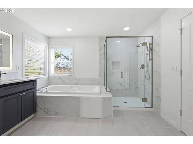 a spacious bathroom with a bathtub a shower a sink and a mirror