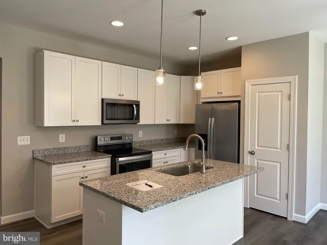 a kitchen with granite countertop a sink a counter top space stainless steel appliances and cabinets