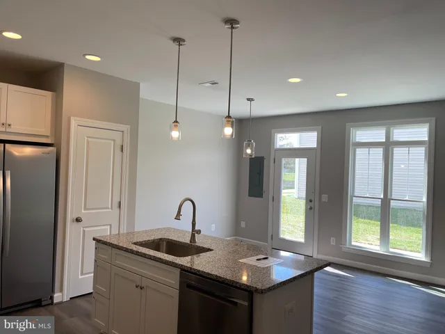 a kitchen with stainless steel appliances granite countertop a sink a refrigerator a center island and a window