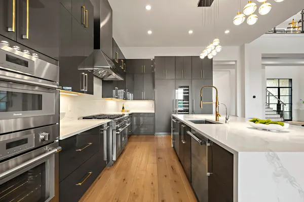 a kitchen with stainless steel appliances granite countertop a sink a stove and a wooden floors