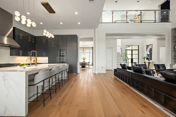 a large kitchen with kitchen island a stove a sink dishwasher and a dining table with wooden floor
