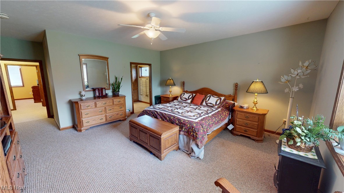 10323 Smith Road Litchfield, OH 44253 - Photo 20 of 50 Bedroom featuring light carpet, baseboards, connected bathroom, and ceiling fan