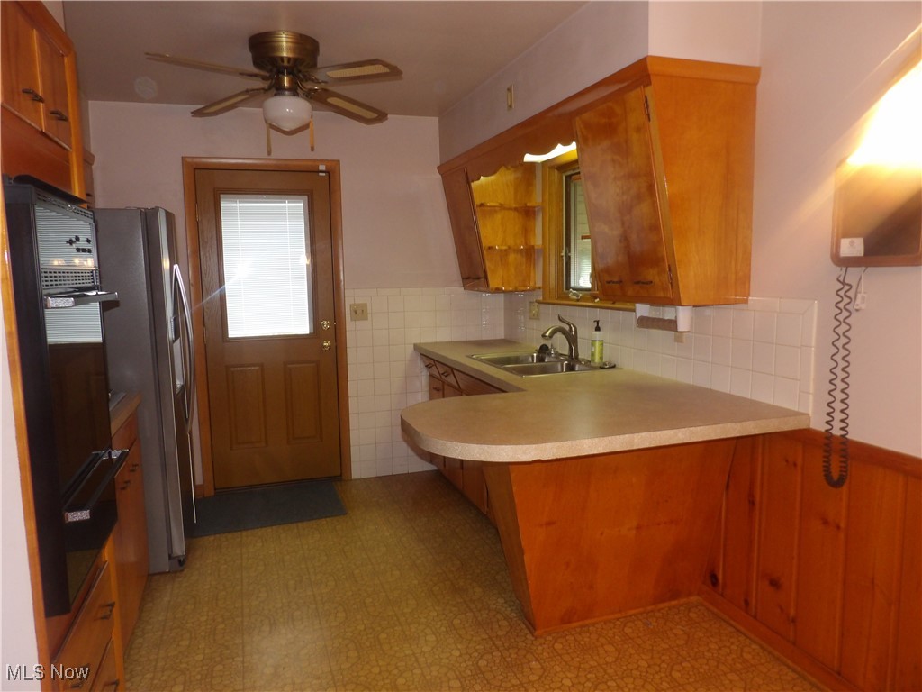 515 Hillman Road Akron, OH 44312 - Photo 6 of 17 Kitchen with brown cabinets, a wainscoted wall, light flooring, light countertops, and a peninsula