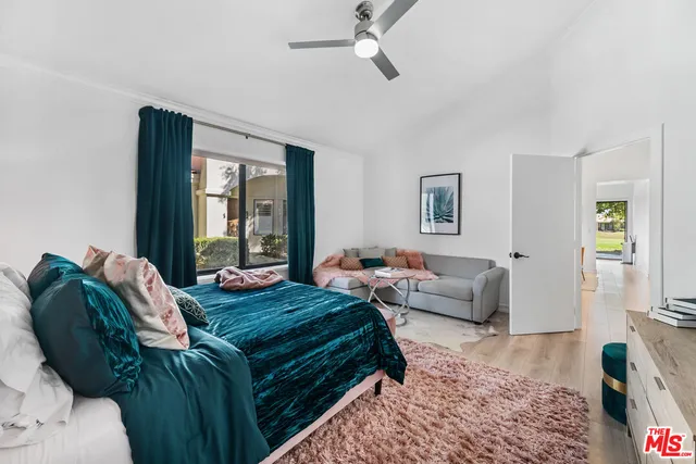 a bedroom with a bed couch and windows