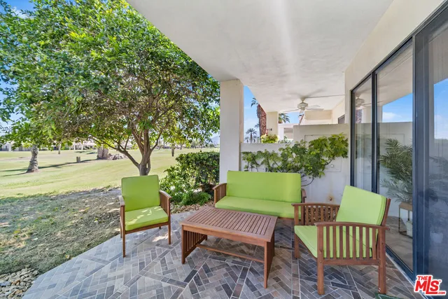 a view of a chair and tables in the patio next to a yard
