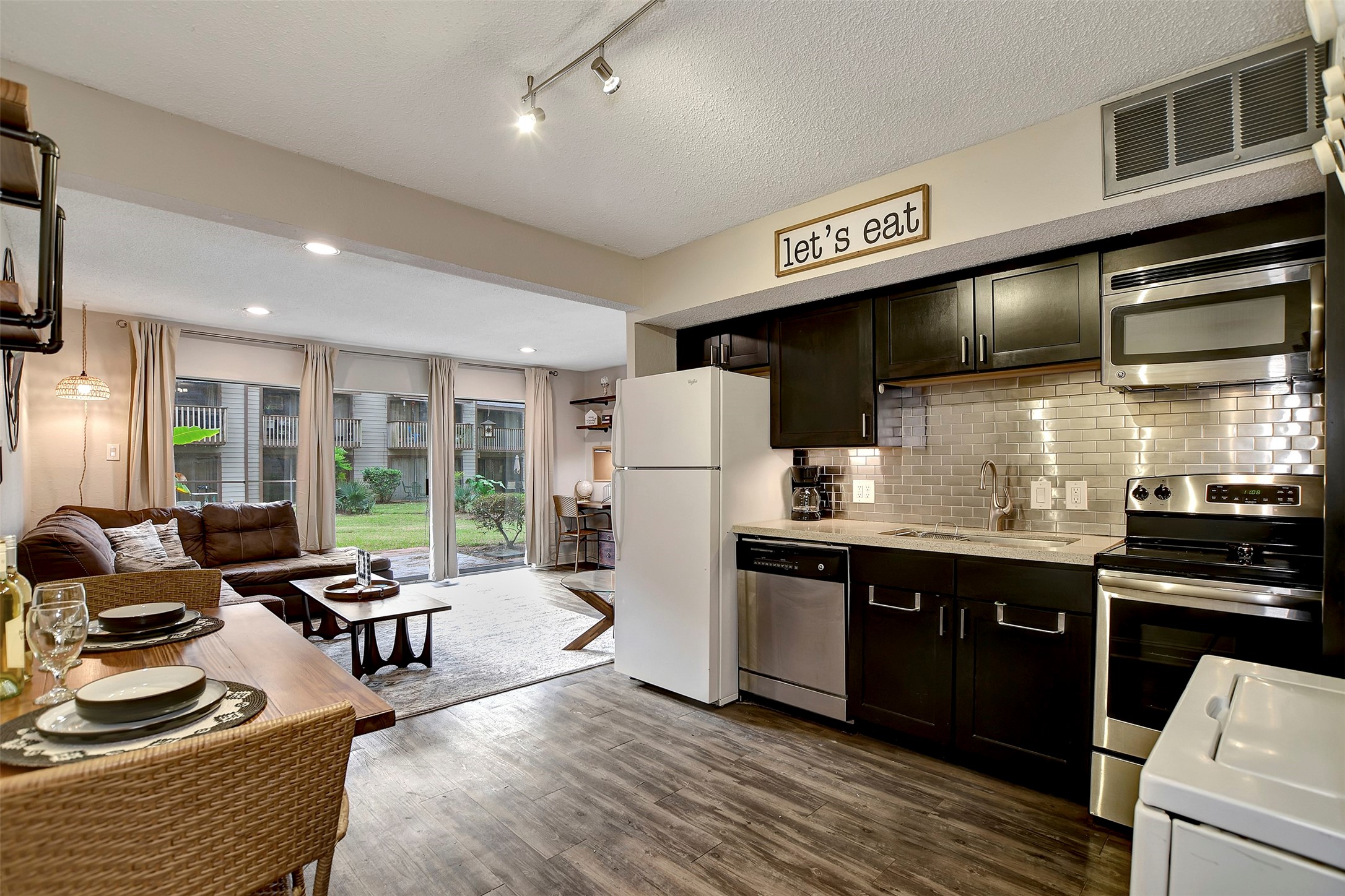 a kitchen with stainless steel appliances kitchen island granite countertop a refrigerator a stove and a sink with wooden floor