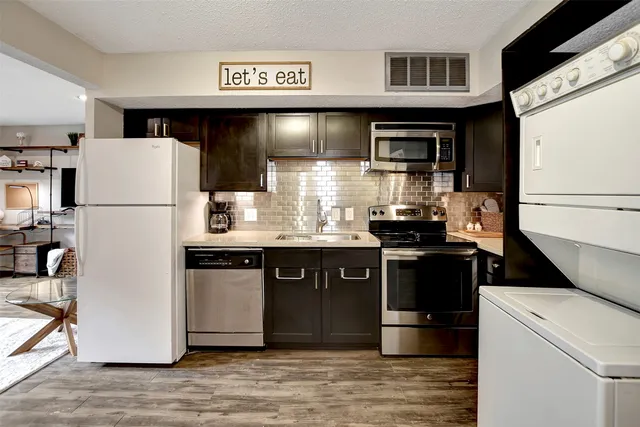 a kitchen with stainless steel appliances granite countertop a refrigerator a stove and a sink