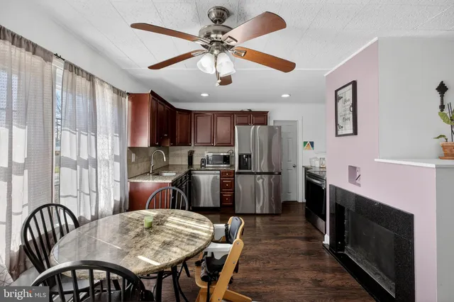 a kitchen with stainless steel appliances granite countertop a dining table chairs refrigerator and sink