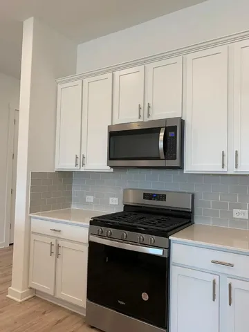 a kitchen with stainless steel appliances granite countertop white cabinets and a stove a oven with white countertops