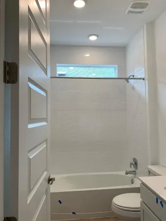 a bathroom with a granite countertop bathtub shower vanity and toilet