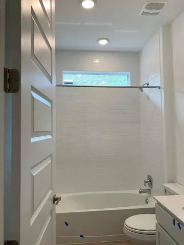 a bathroom with a granite countertop bathtub shower vanity and toilet