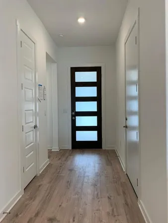 an empty room with wooden floor closet and windows