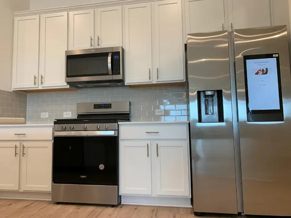 a kitchen with stainless steel appliances granite countertop a stove a microwave and a refrigerator