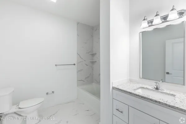 a bathroom with a granite countertop sink a toilet and a mirror