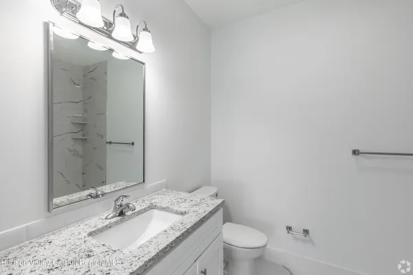 a bathroom with a granite countertop sink a toilet and shower