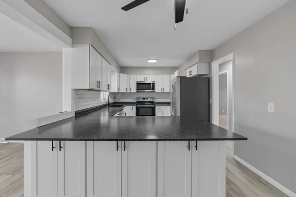 a kitchen with stainless steel appliances granite countertop a sink a stove and a refrigerator