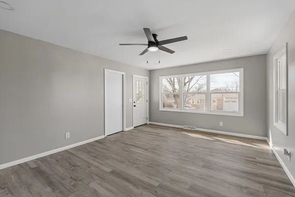 a view of an empty room with a window and wooden floor