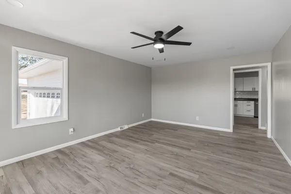 a view of an empty room with wooden floor and a window