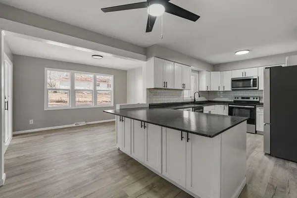 a kitchen with stainless steel appliances granite countertop a sink a stove and refrigerator