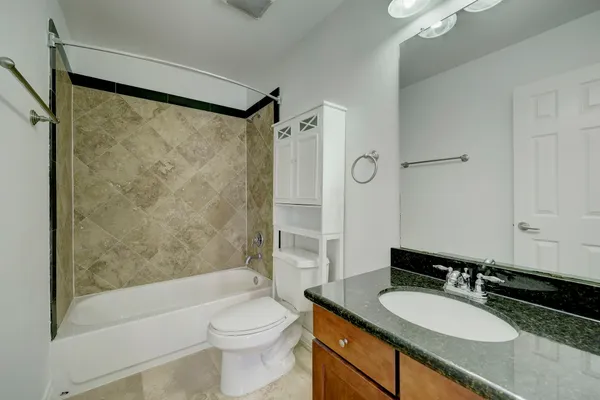 a bathroom with a granite countertop sink toilet mirror and shower