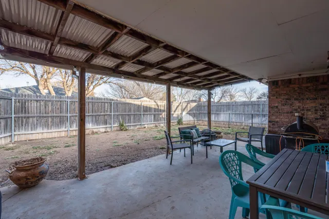 a view of a patio with table and chairs and wooden fence