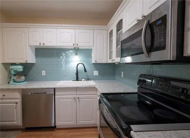 a kitchen with stainless steel appliances granite countertop a sink a stove and cabinets