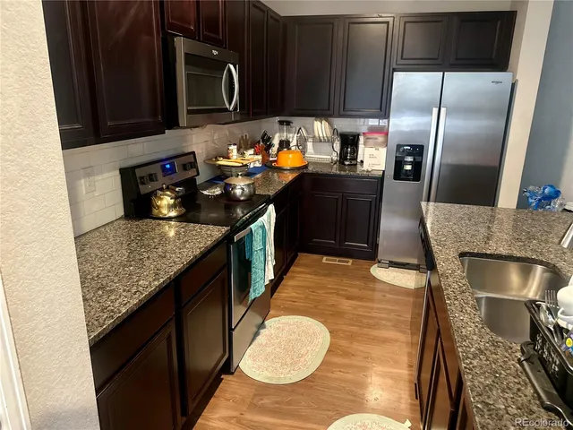 a kitchen with stainless steel appliances granite countertop a sink a stove and a refrigerator