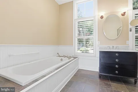 a spacious bathroom with a tub sink and mirror