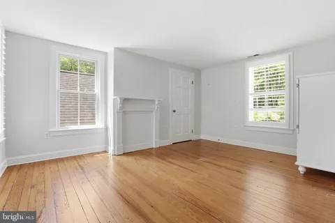 an empty room with wooden floor cabinet and windows